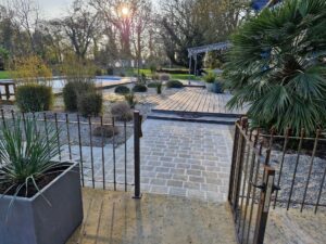 Jardin à Rennes avec allée en pavés de granit, terrasse bois et plantations paysagères